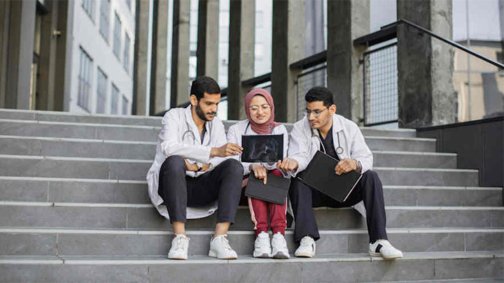 Three medical students sitting on steps.