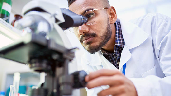 Medical student looking down a microscope.