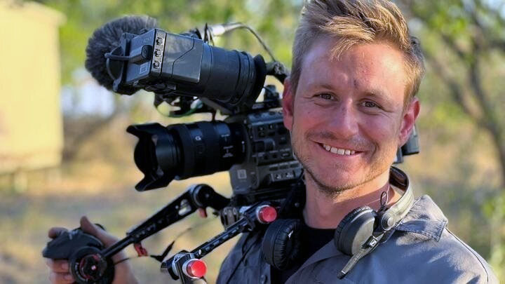 Tom Parry, a Biosciences graduate now working at the BBC, holding a tv camera.