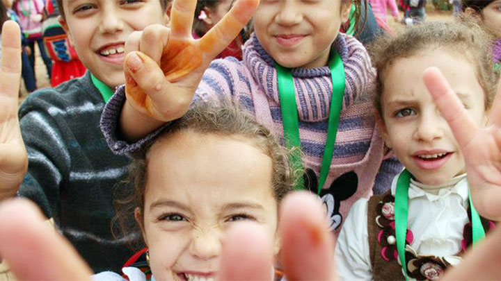 A group of children making peace signs with their fingers.
