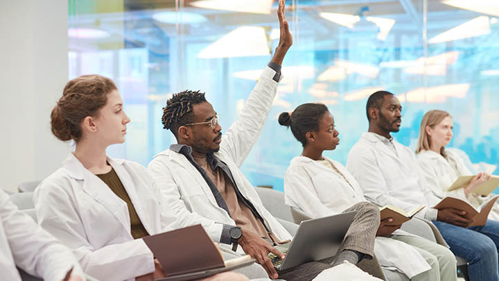 A medical student raises his hand in class.