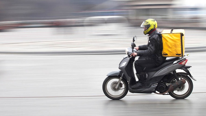 A delivery driver on a motorbike.