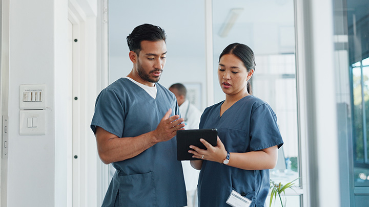 Two healthcare professionals discussing a patient's notes in a hospital.