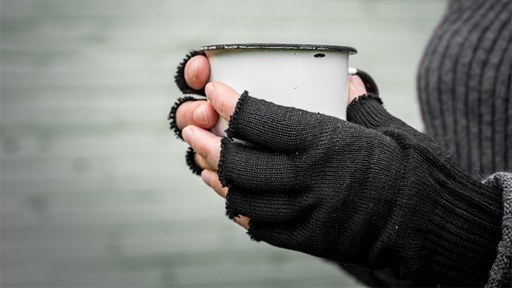 A homeless person holding a hot drink.