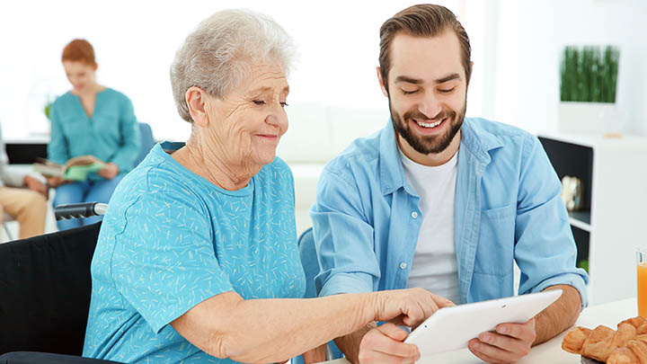 A researcher and an older lady looking at a tablet pc.