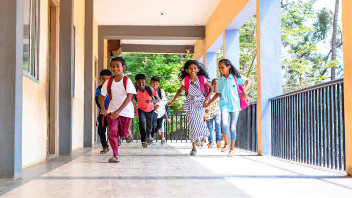 South Asian children running outside a school.