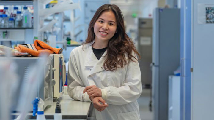 Postgraduate student smiling at the camera in a lab setting.