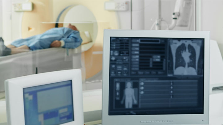 A computer screen showing a CT scan of a patient, with patient in background.