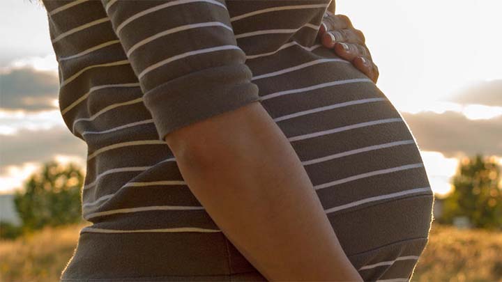 Pregnant person holding their belly.