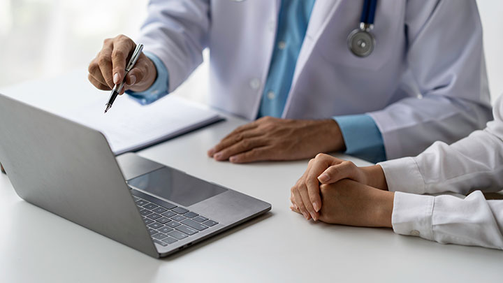 Two people in a clinical setting working together on a laptop.