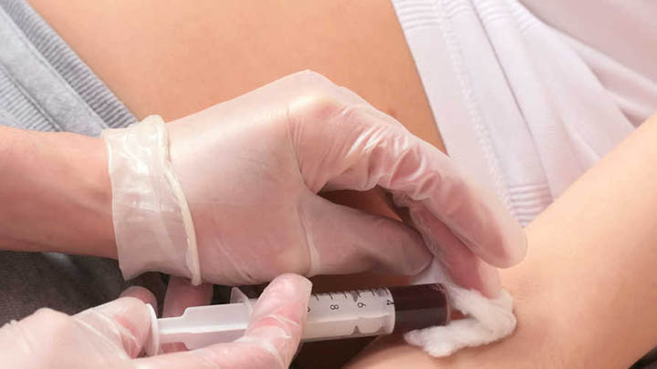 A doctor takes a blood sample from a pregnant woman.