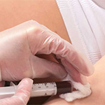 A doctor takes a blood sample from a pregnant woman.