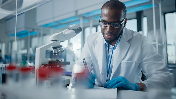 A researcher in the lab writing notes about an experiment.