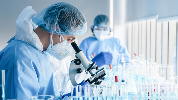 Researcher looking down a microscope in the lab.