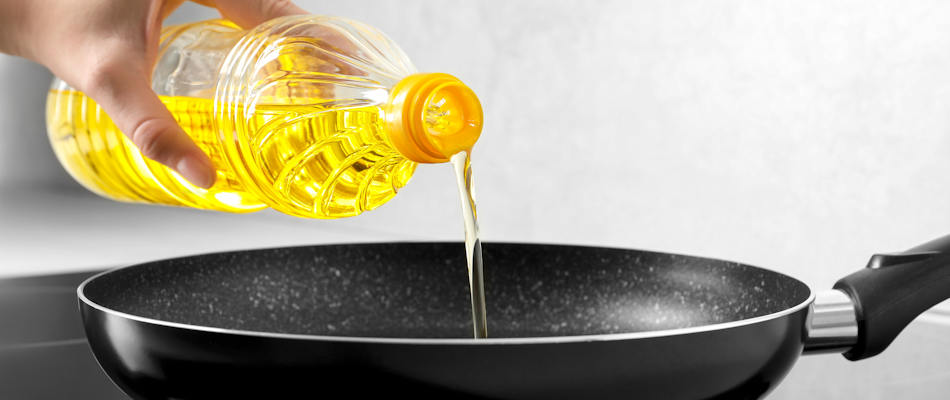Oil being poured into a frying pan.