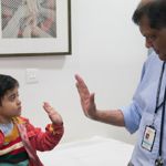 Vaskar Saha high fiving a young boy.