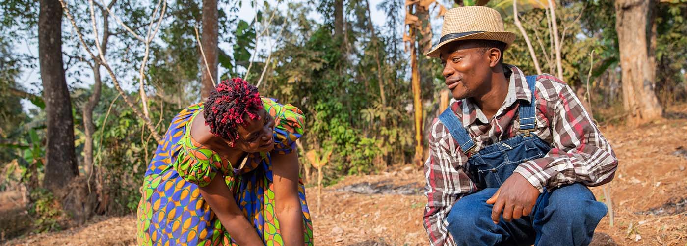 Two African farmers talking while hoeing the fields.