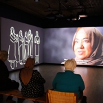 Suzanne Johnson, Binish Khatoon and Ncazelo Ncube watching a film featuring Asian women at the Manchester Museum.