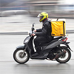 A person making a fast-food delivery on a moped.