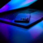 A smartphone on a laptop keyboard, bathed in blue light.