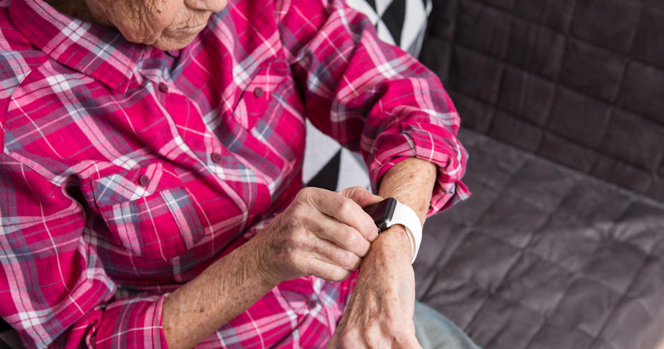 An older woman checking a watch capable of collecting health data.