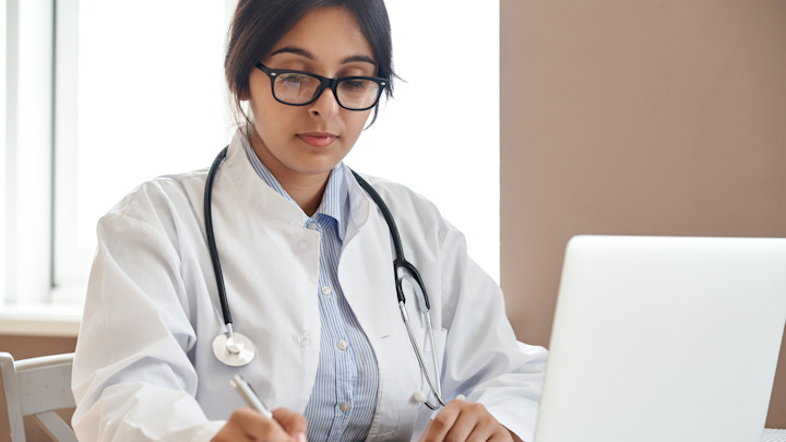 A female Asian doctor using a laptop.