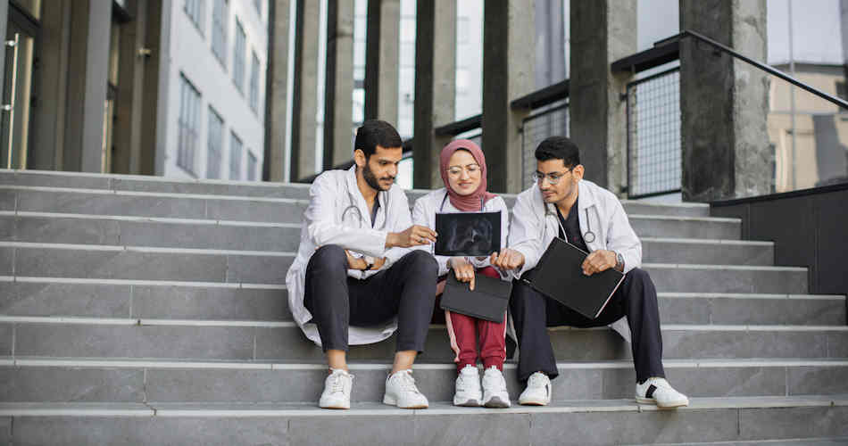 Three medical students sitting on steps.