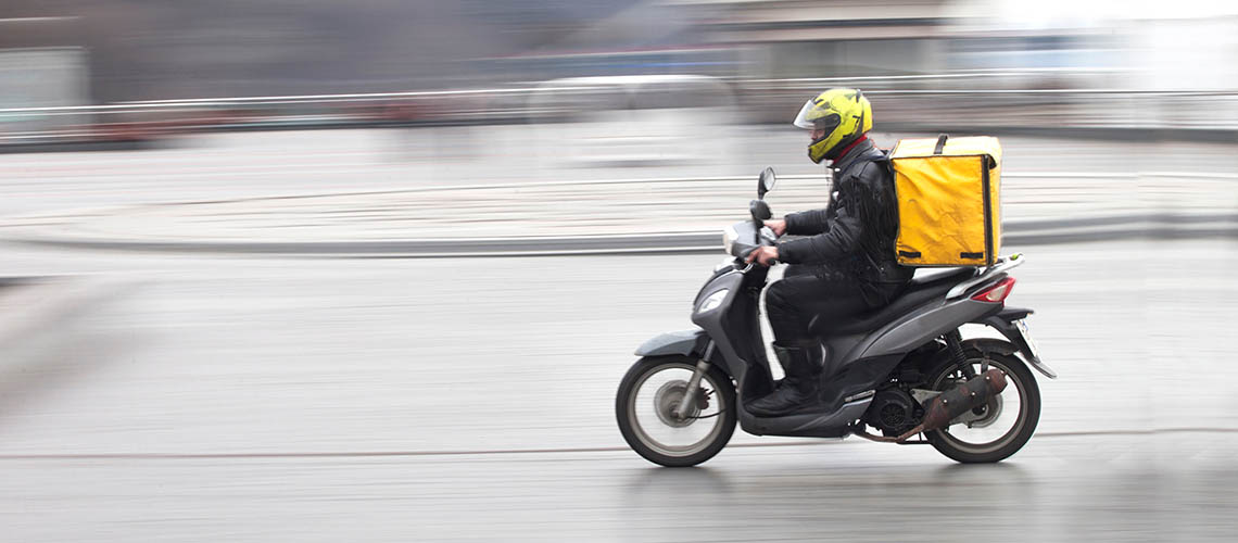 A person making a fast-food delivery on a moped.
