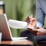 A psychiatrist taking notes in front of a laptop.