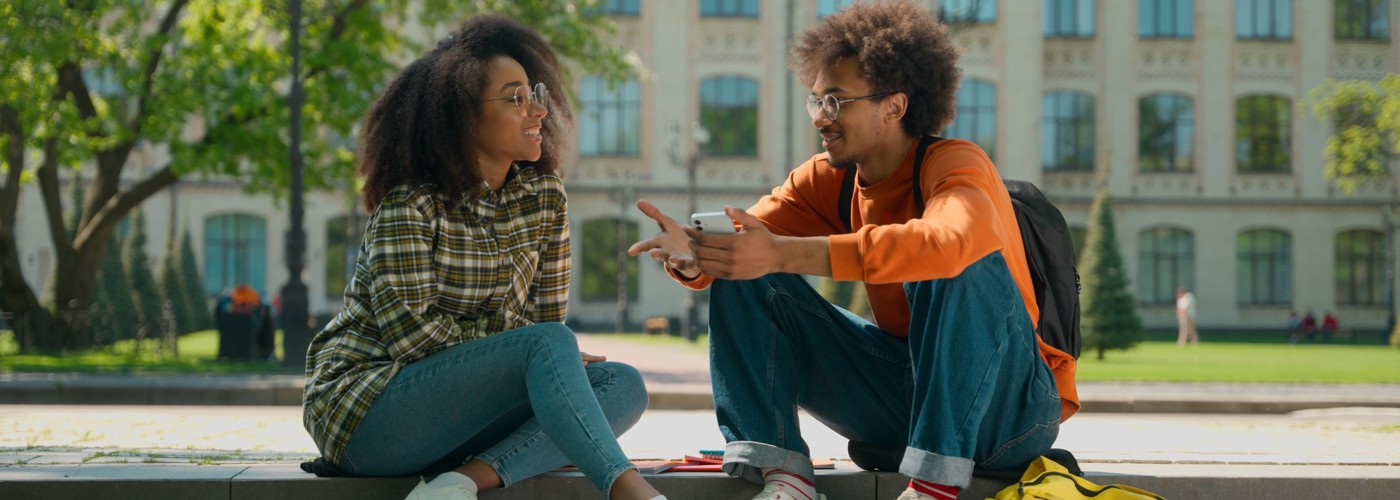 Two Black people talking on some steps.