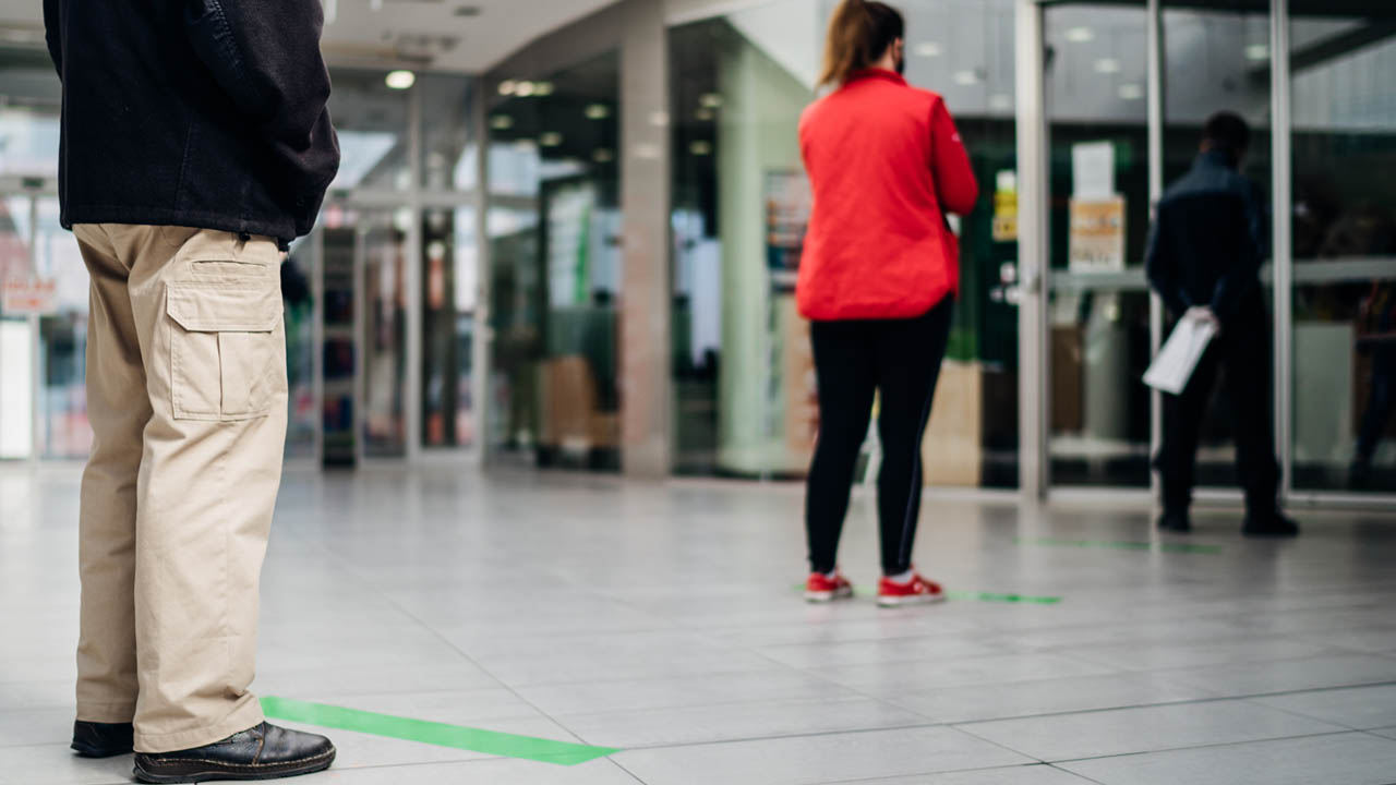 People standing in line front of bank/store due to coronavirus pandemic safety guideline.COVID-19 safe social distancing practice.Quarantine financial crisis,banking,loans.Spaced out queue.Crowd-limit