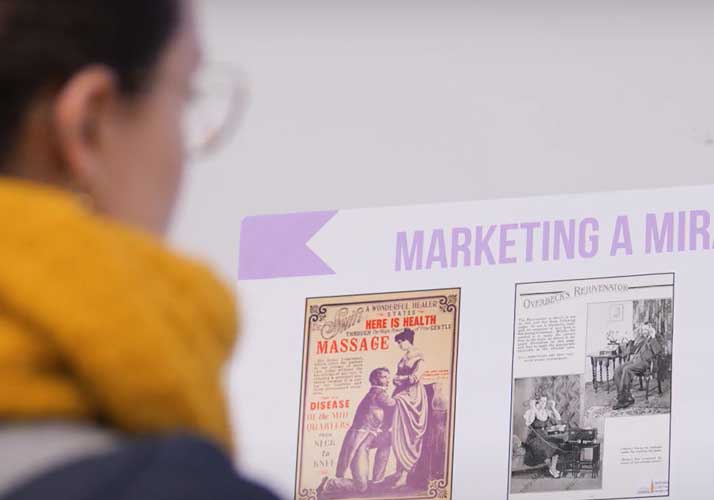 A woman reading old adverts for healthcare treatments.