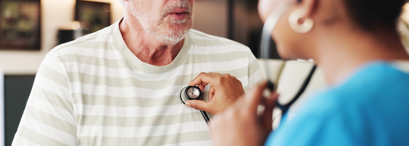 A doctor listening to the heartbeat of a male patient.