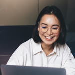 A young woman at a laptop with a man sitting next to her. Both are smiling.