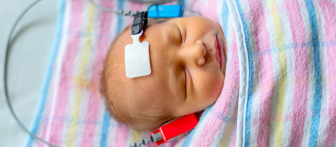 A newborn baby having a hearing test while asleep.