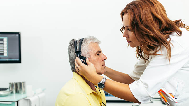 An audiologist positioning headphones on a patient during a hearing test.