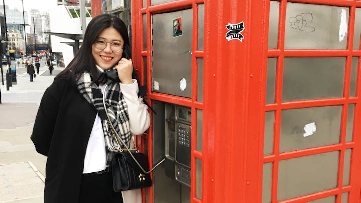 Lin Wu standing next to a red telephone box.