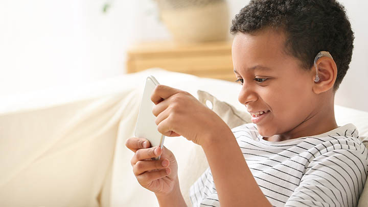 A young boy playing a game on a mobile phone.