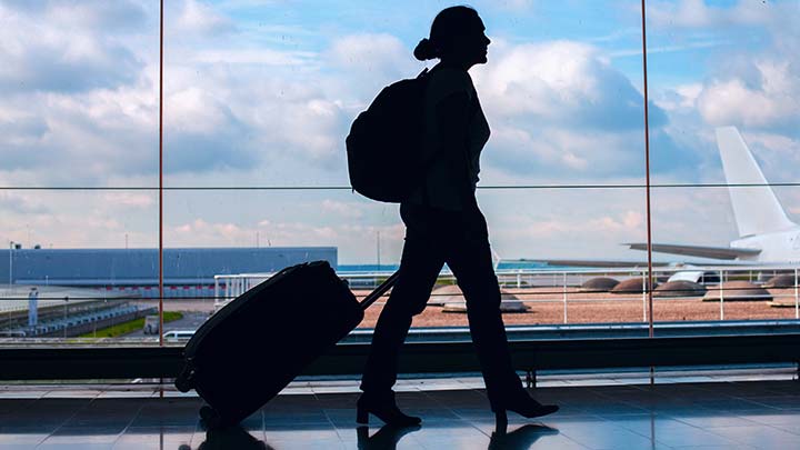 A passenger walking with luggage to their boarding gate at the airport.