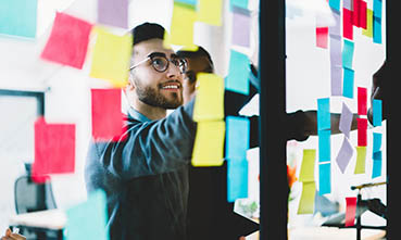 A student studies a glass wall of sticky notes.