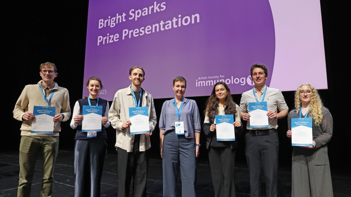 Seven people holding Bright Spark prize certificates at an immunology conference.