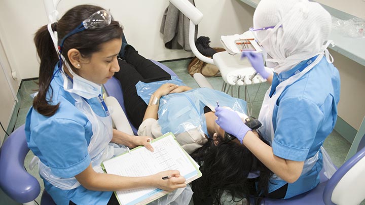 Two dentistry students practising a procedure on a dental patient.