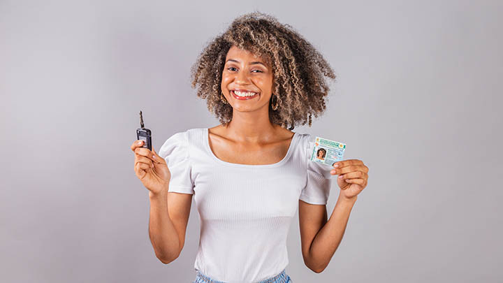 A girl holding a car key and driving licence.