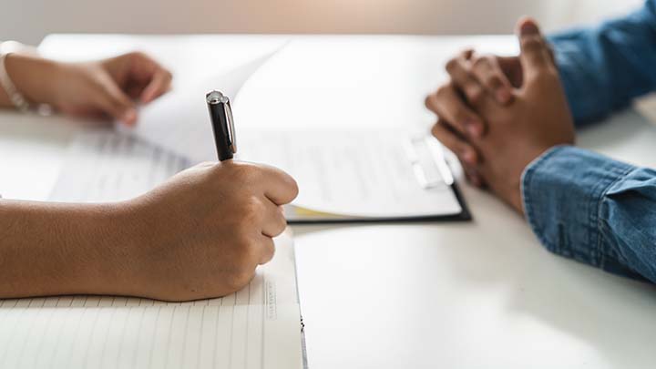 An interviewer making notes during an interview.