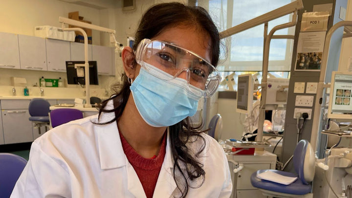 A photo of Jeena Patel in her lab coat and mask.