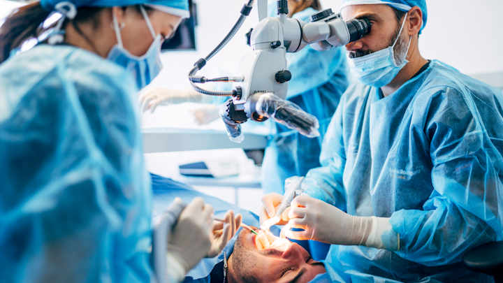 Dentist and assistant performing a dental procedure on a patient.