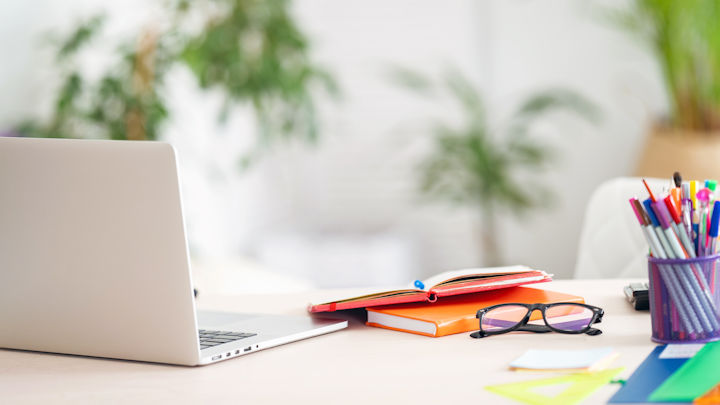 A photo of a desk with a laptop and stationery on it.