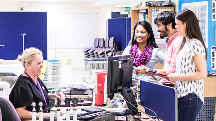 Medical students chatting with a healthcare professional on a hospital ward.