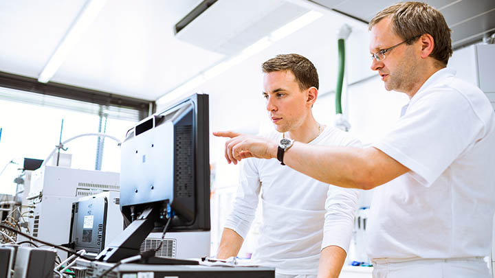 A student and tutor discuss information on a computer screen.
