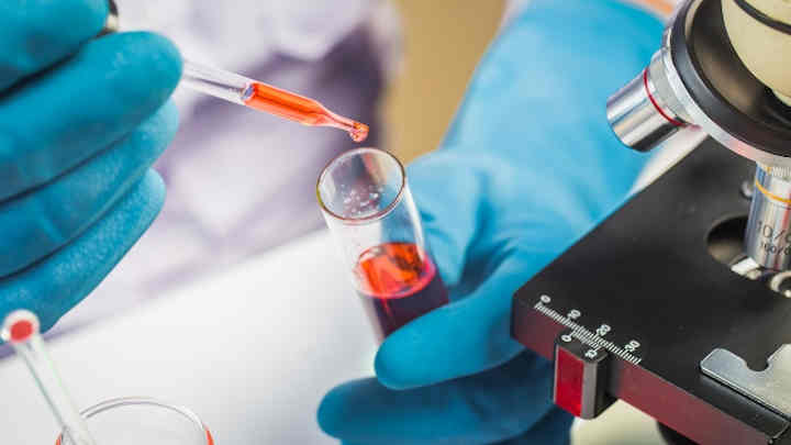 A researcher using a pipette to gather a sample of liquid.